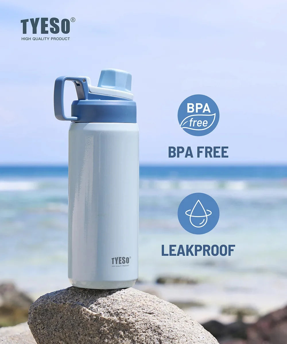 A white insulated stainless steel water bottle with a blue cap is shown outdoors on a rock near the sea.