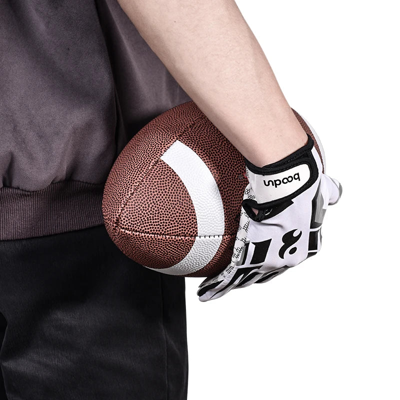 Une main portant des vêtements de sport noirs tient un gant de sport en silicone anti-dérapant brun et blanc.