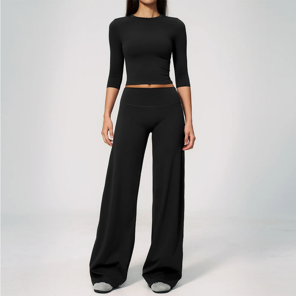 A woman wearing a black long-sleeved top and matching high-waisted black yoga leggings set.