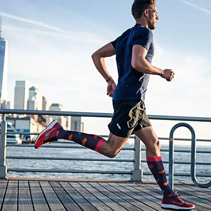 A man wearing premium nurse compression socks is jogging outdoors on a wooden deck with a city skyline in the background.