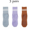 Three pairs of grip socks in light blue, purple, and brown for Pilates, yoga, and barre