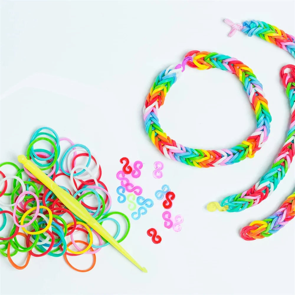 Una colección de bandas elásticas de telar coloridas y una herramienta amarilla, mostradas sobre un fondo blanco.