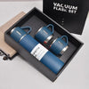 A blue stainless steel vacuum flask bottle is displayed inside a black box with a black fabric bag in the background.