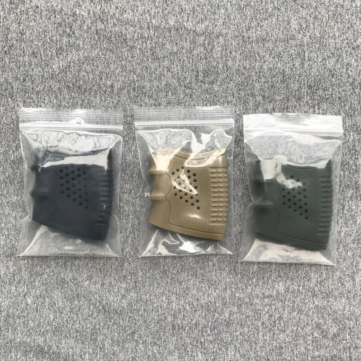 Drei durchsichtige Plastiktaschen mit rutschfesten Gummi-Handschuh-Ärmeln in Schwarz, Tan und Dunkelgrün.