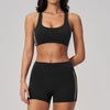 A woman wearing a black two-piece yoga and sports tracksuit set consisting of a sports bra top and matching shorts.