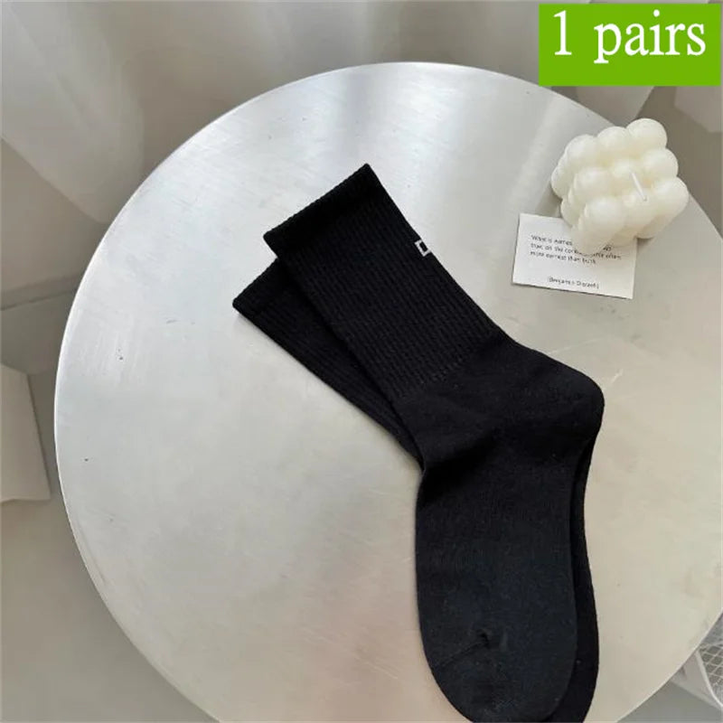 Ein Paar schwarze, atmungsaktive, rutschfeste Yoga- und Fitnesssocken auf einer weißen Oberfläche.