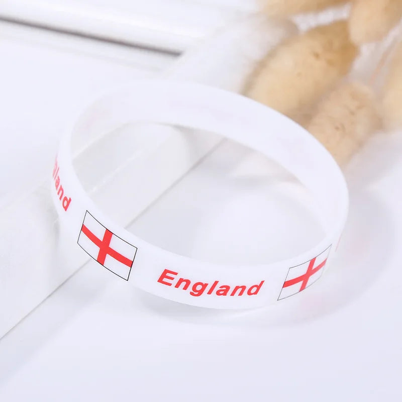White silicone wristband with the flag of England printed on it, resting on a white surface.