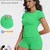 A woman models a bright green sports casual tracksuit consisting of a short-sleeved top and matching shorts.