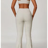 A woman models a beige three-piece yoga sports set consisting of a cropped top, leggings, and matching bottoms.