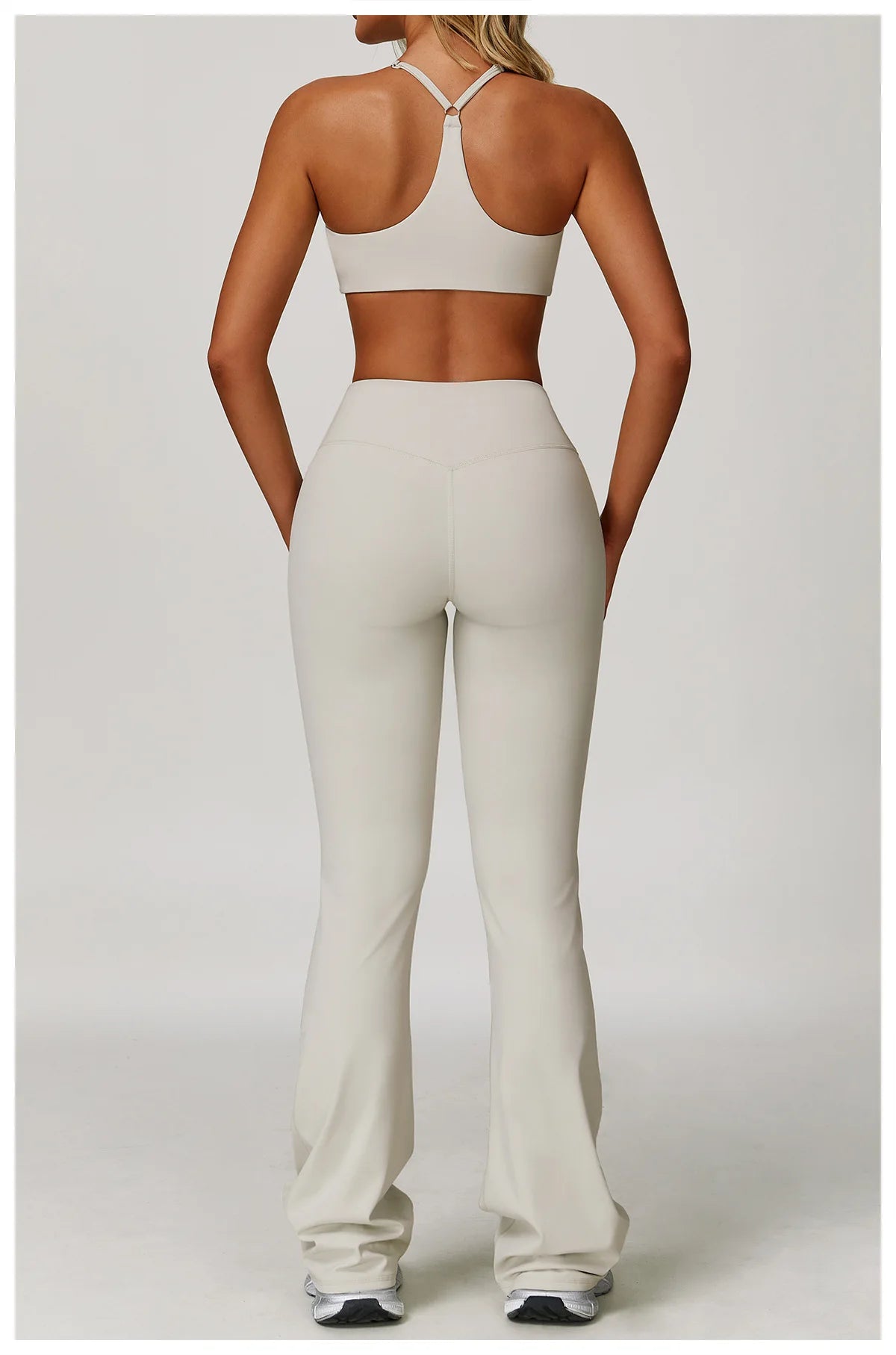 A woman models a beige three-piece yoga sports set consisting of a cropped top, leggings, and matching bottoms.