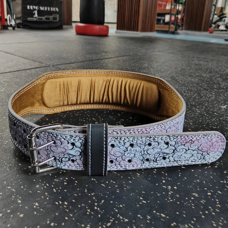 A purple patterned weightlifting belt with a black buckle resting on a dark gray floor.