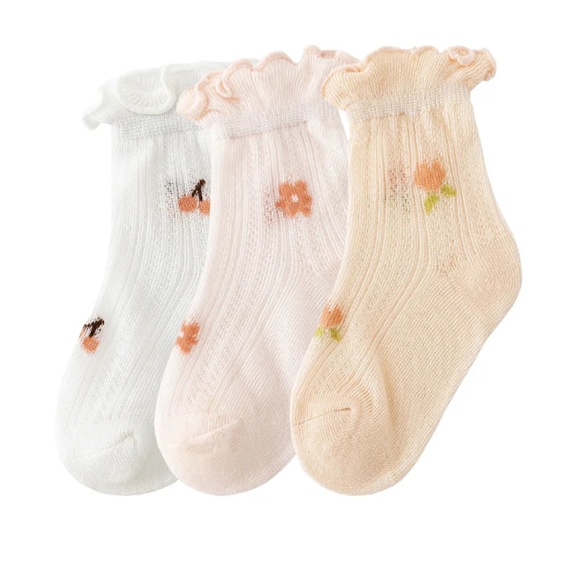 A pack of three thin summer casual baby socks in white, pink, and beige with floral patterns.