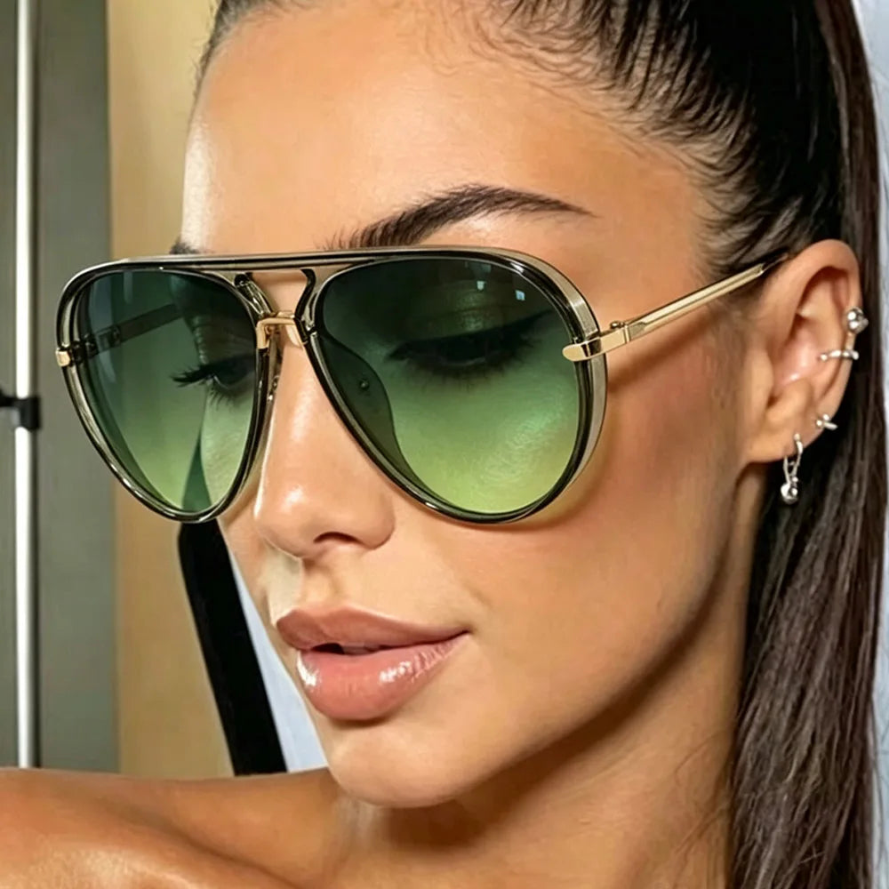 A close-up of a woman wearing gold-framed olive green pilot sunglasses.