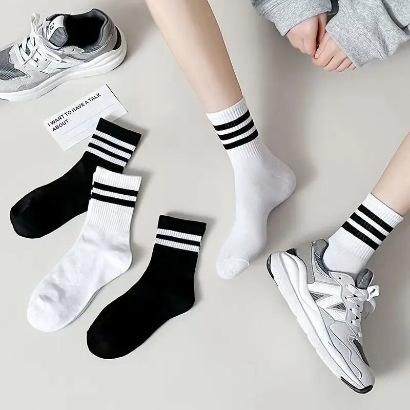 A flat lay showing various black and white breathable cotton sport socks and a pair of athletic shoes.