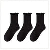 A set of three black cotton ruffle ankle socks displayed against a white background.