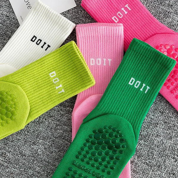 A collection of pink, white, and lime green breathable anti-slip yoga and fitness socks laid out on a gray surface.