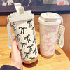 A hand holds a double-wall insulated stainless steel travel mug with a white lid and a pink floral pattern.