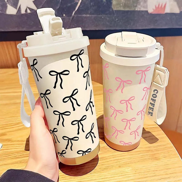 A hand holds a double-wall insulated stainless steel travel mug with a white lid and a pink floral pattern.