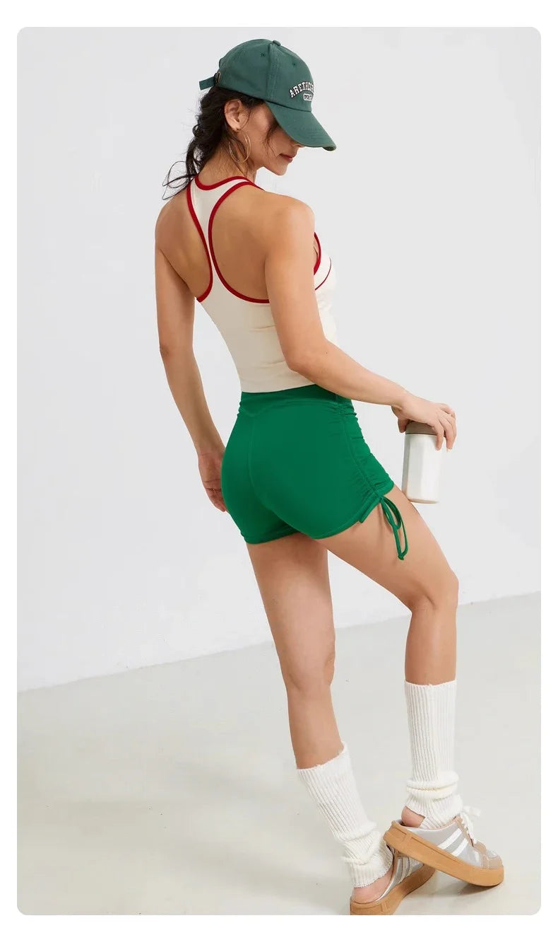 A woman wearing performance yoga shorts and a green cap poses in a side view.