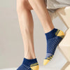 A close-up of a man's legs and feet wearing navy blue athletic knit ankle socks with yellow accents.