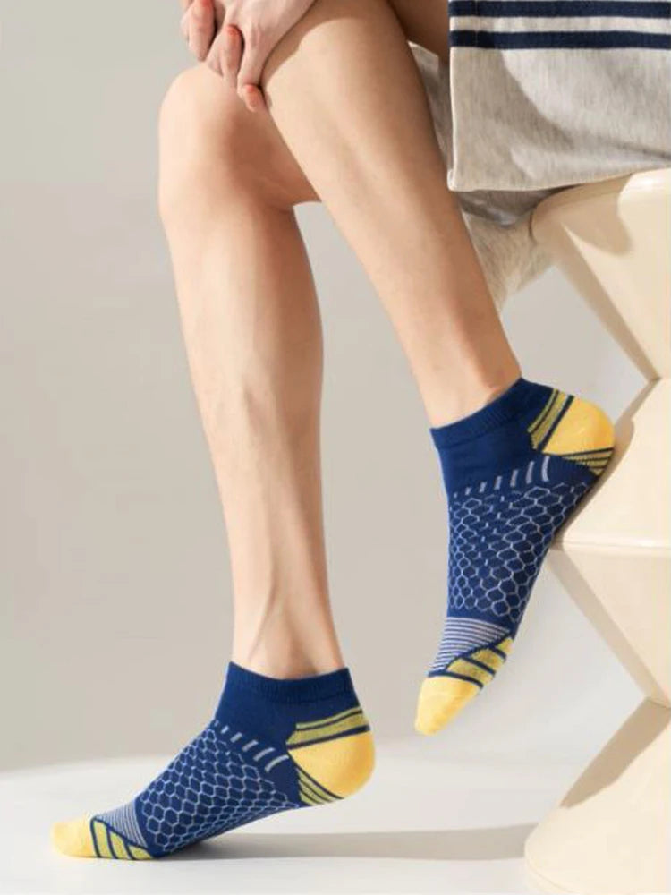 A close-up of a man's legs and feet wearing navy blue athletic knit ankle socks with yellow accents.