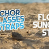 Anchor glasses straps and floating sunglasses straps displayed on a sandy beach near the ocean.