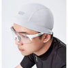 A man wearing a light gray quick dry cycling cap and clear protective eyewear.