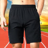 Black men's quick dry jogging shorts worn by a person on a running track.