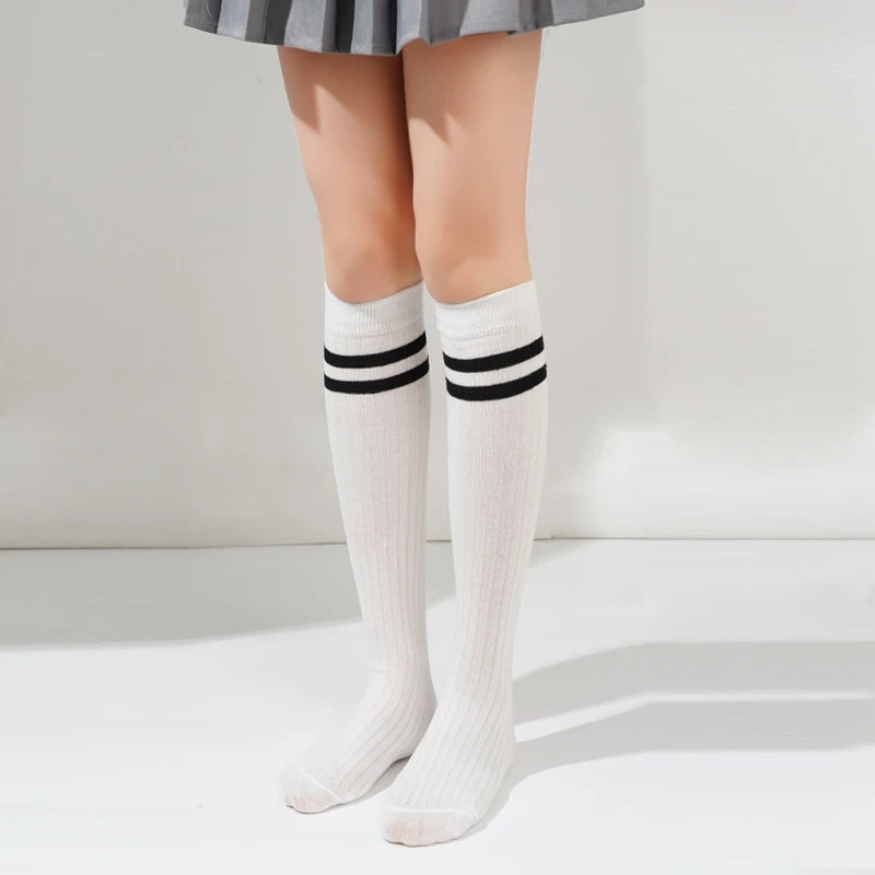 White cotton knee high socks with black stripes worn by a person.