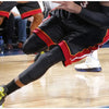 A person wearing black compression knee pads with red trim and black pants is shown during a sports activity.