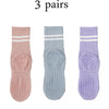 Three pairs of pink, light blue, and purple Pilates grip socks for yoga and barre