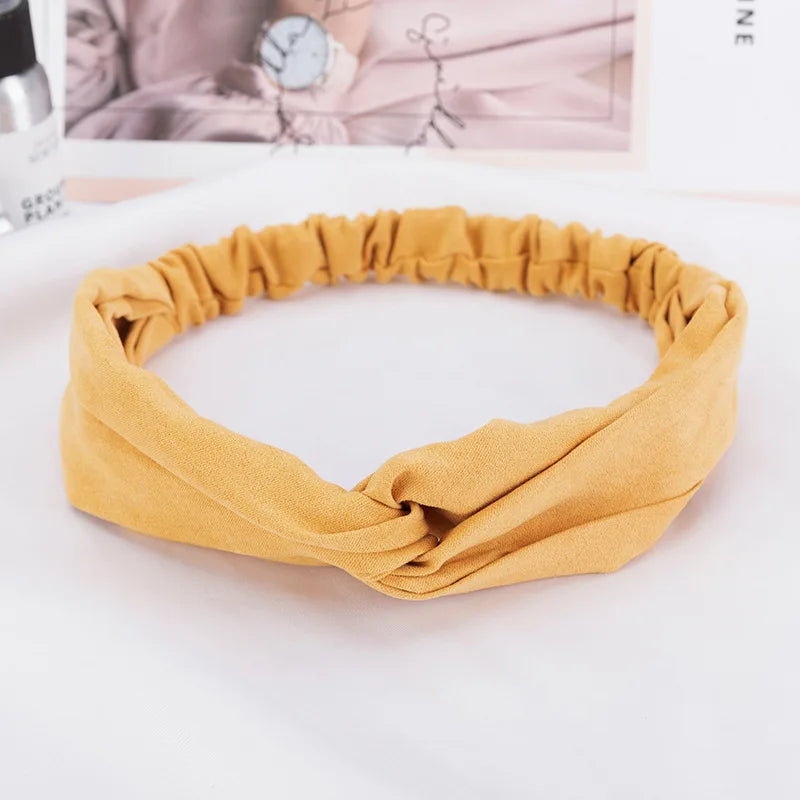 A mustard yellow bohemian chiffon headband is shown rolled and laid on a white surface.
