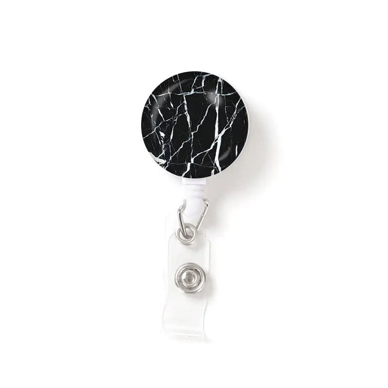 A round black marble-patterned ID badge reel keychain attached to a clear plastic holder.