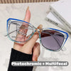 Eine Hand hält eine klare photochromische multifokale Lesebrille mit blauen Rahmen vor weißem Hintergrund.