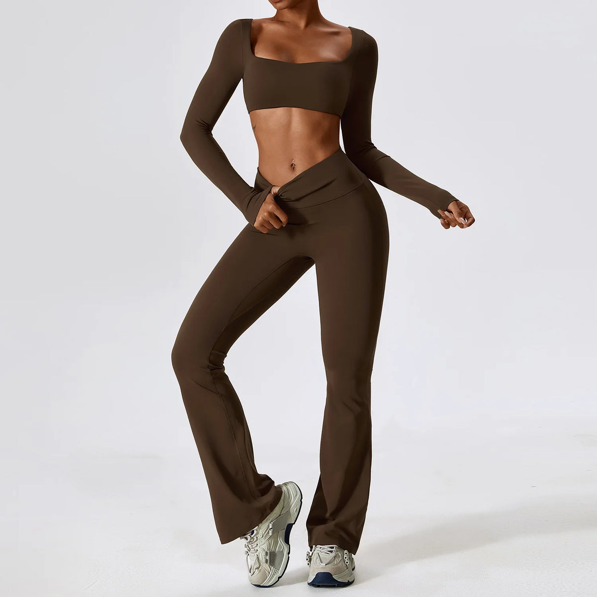 A woman wearing a brown women's performance tracksuit set consisting of a cropped top and matching trousers.