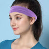 A woman wearing a purple stretchable cotton sweat absorbing headband on her forehead against a light blue background.