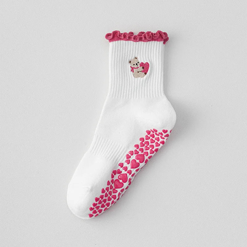 Chaussettes de yoga blanches avec bordure rose et une petite broderie d'ours sur le pied