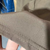 Close-up of a brown men's stretch performance drawstring pant fabric being held by a hand.
