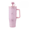 A pink insulated thermos mug decorated with white pearl-like patterns and topped with a pink bow.