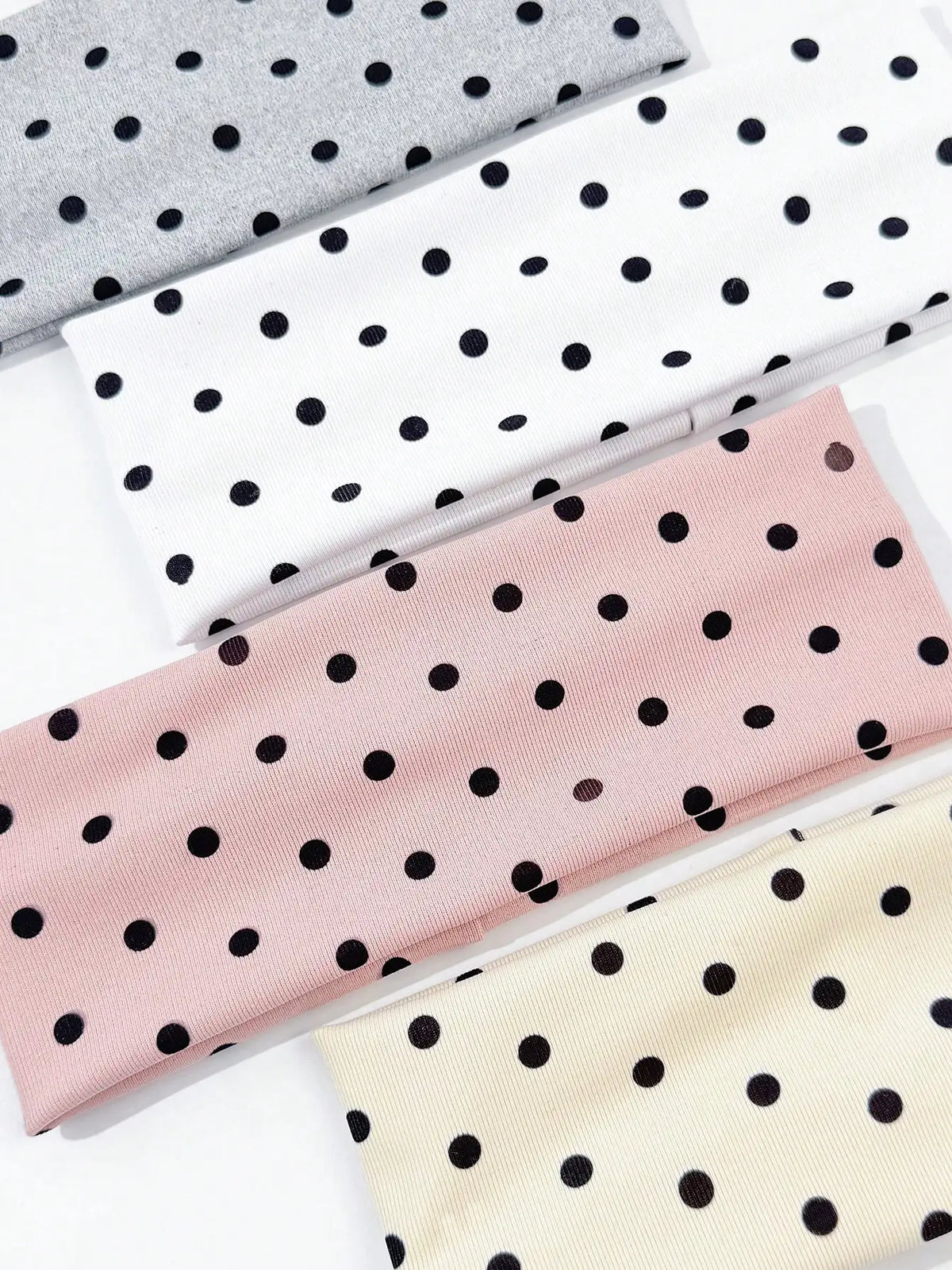A set of four polka dot elastic hair bands in gray, white, pink, and cream colors.