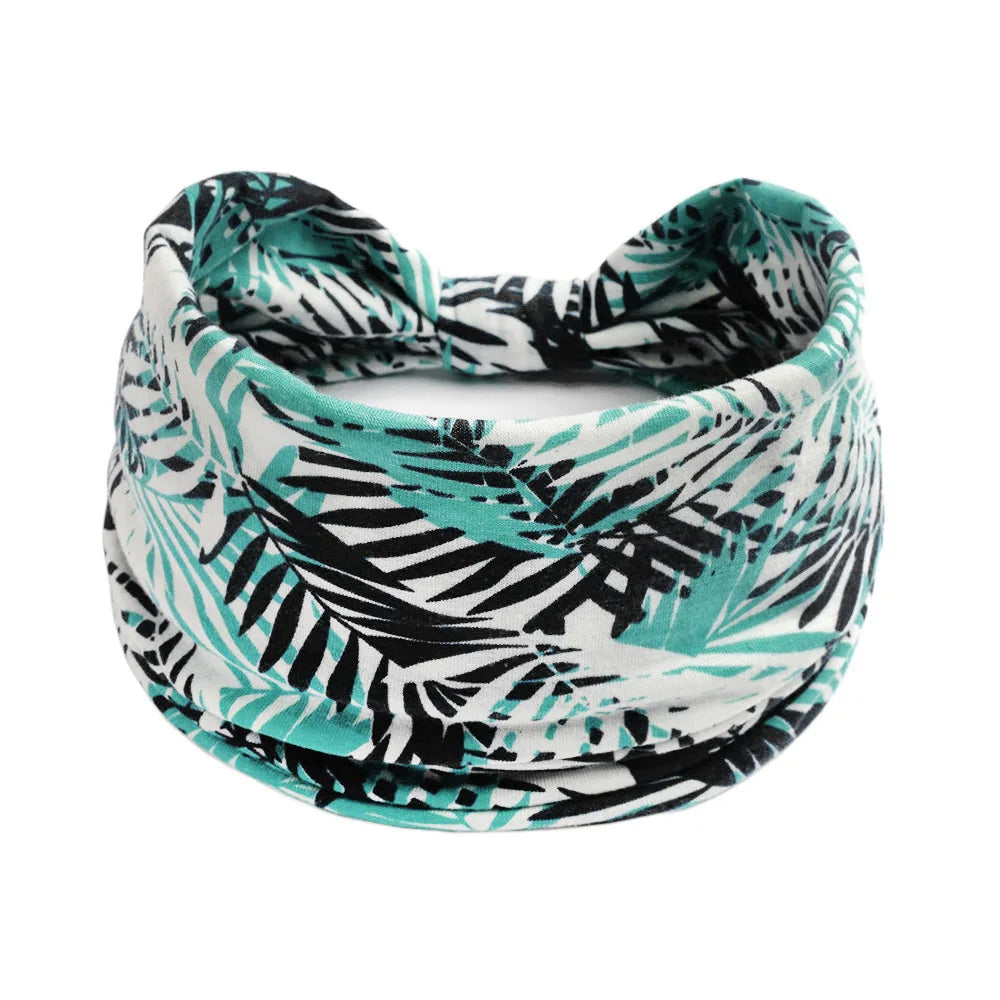 A black and teal tropical leaf patterned cotton stretch headband worn around the head.