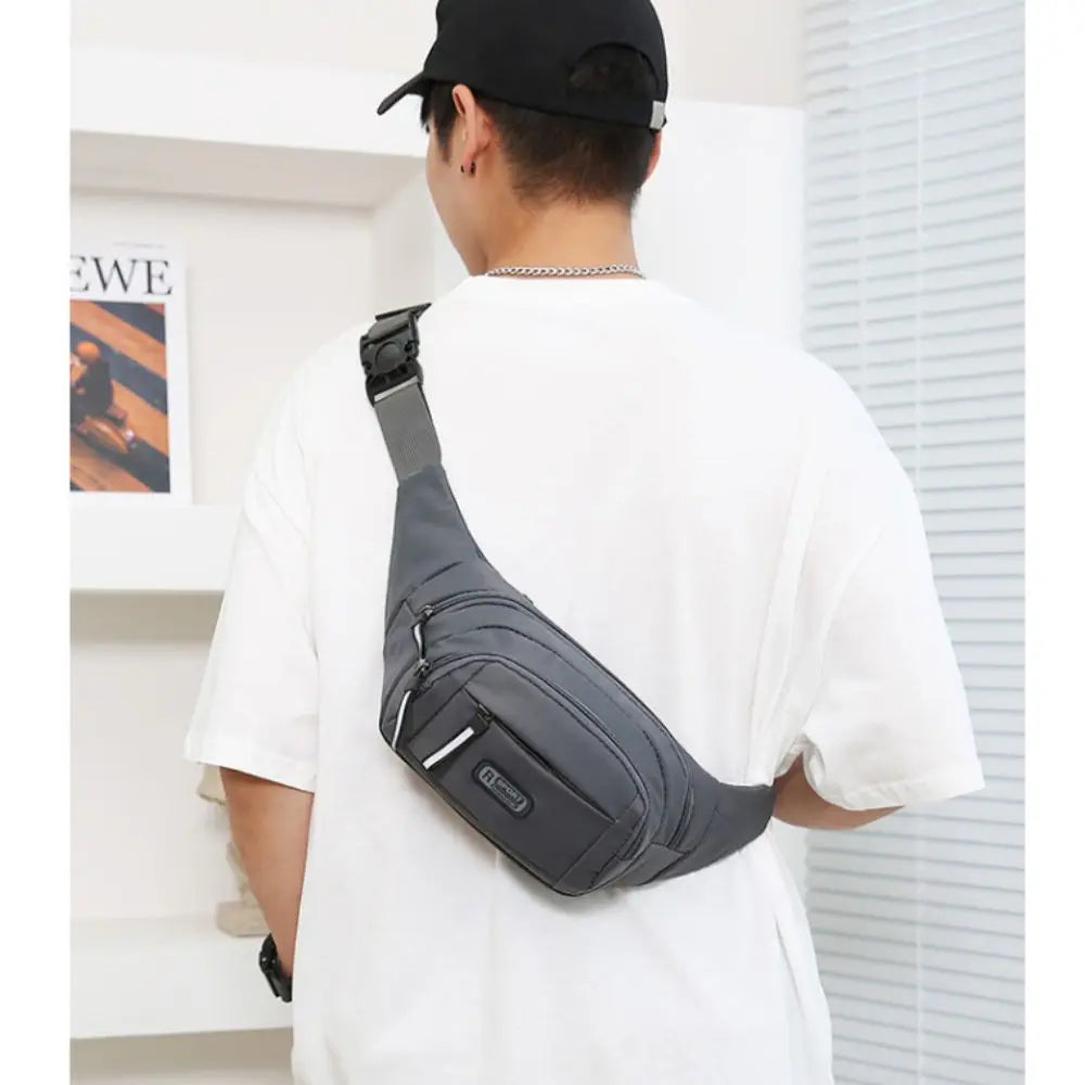 A man wearing a black cap and white shirt is shown from the back carrying a black nylon waist bag.