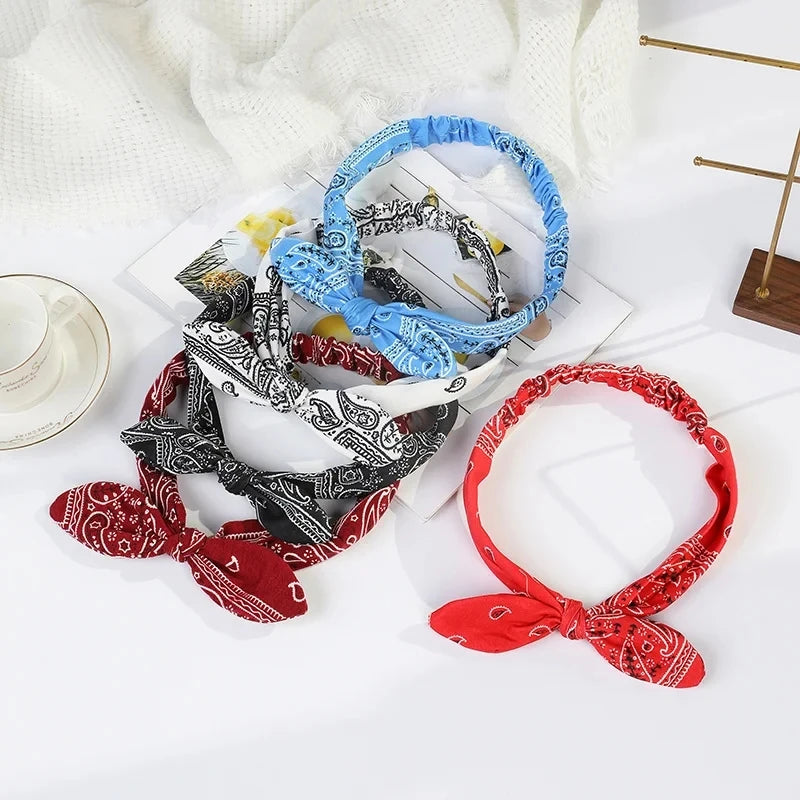 A collection of boho paisley elastic hair headbands in blue, black, and red are displayed on a white surface.