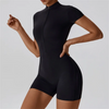 A woman wearing a black seamless yoga jumpsuit, shown from the side.
