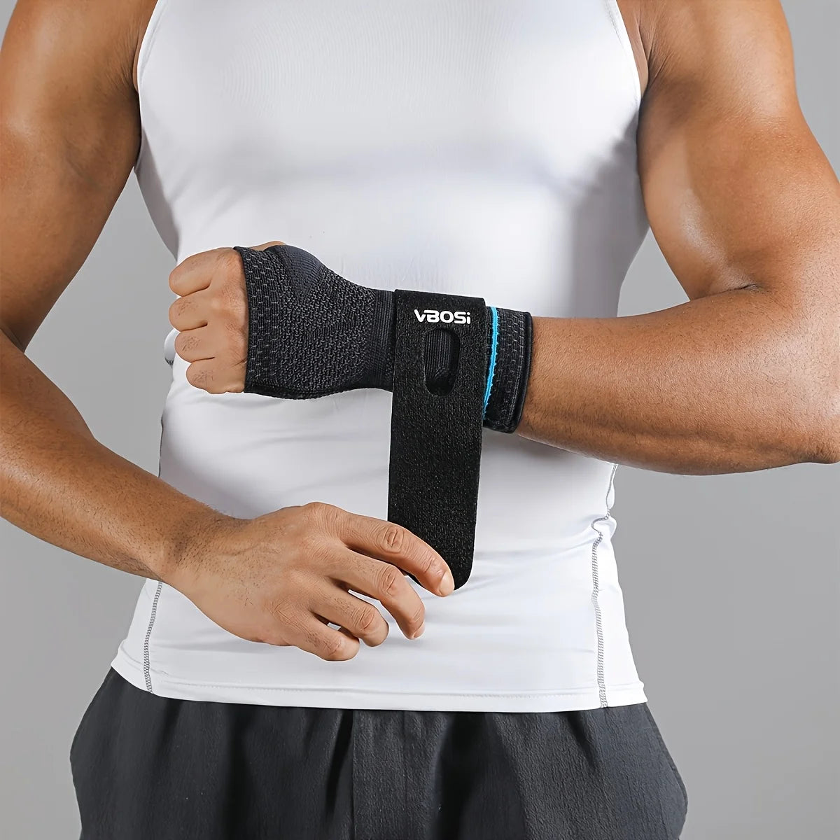 A person wearing a white tank top is shown holding a black VaoSi wrist palm support brace on their forearm.