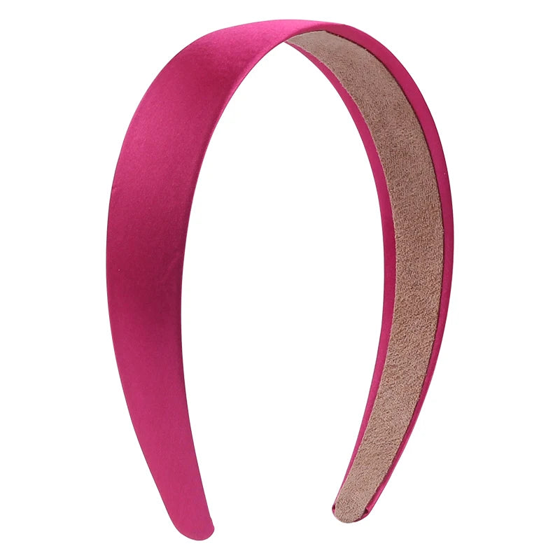 A pink satin hair band with a suede-colored lining shown in a curved shape.