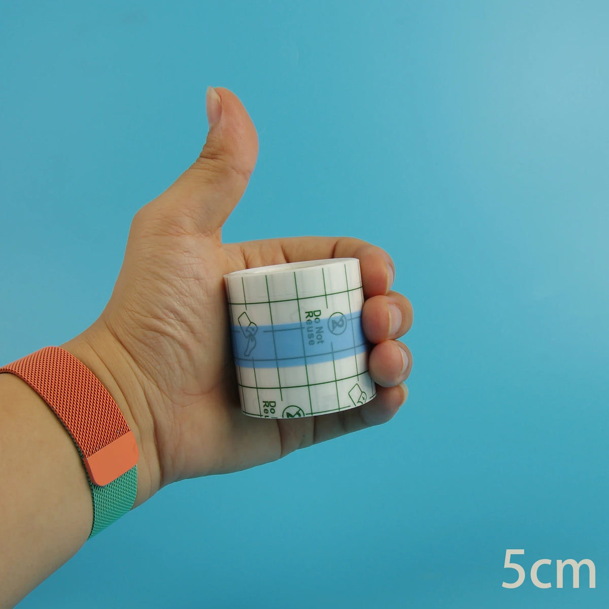 Eine Hand hält eine Rolle wasserfeste Tattoo-Heilfolie vor einem blauen Hintergrund.
