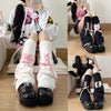 A person wearing black combat boots and white leg warmers with pink bows, styled as Gothic Lolita heart bow leg warmers.