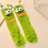 Pair of funny plush caterpillar floor socks with green fuzzy texture and yellow and blue accents