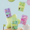 A collection of colorful double-walled drinking cups and straws in purple, green, and pink shades